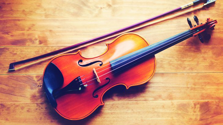 Violin and bow lying on a wooden textured table