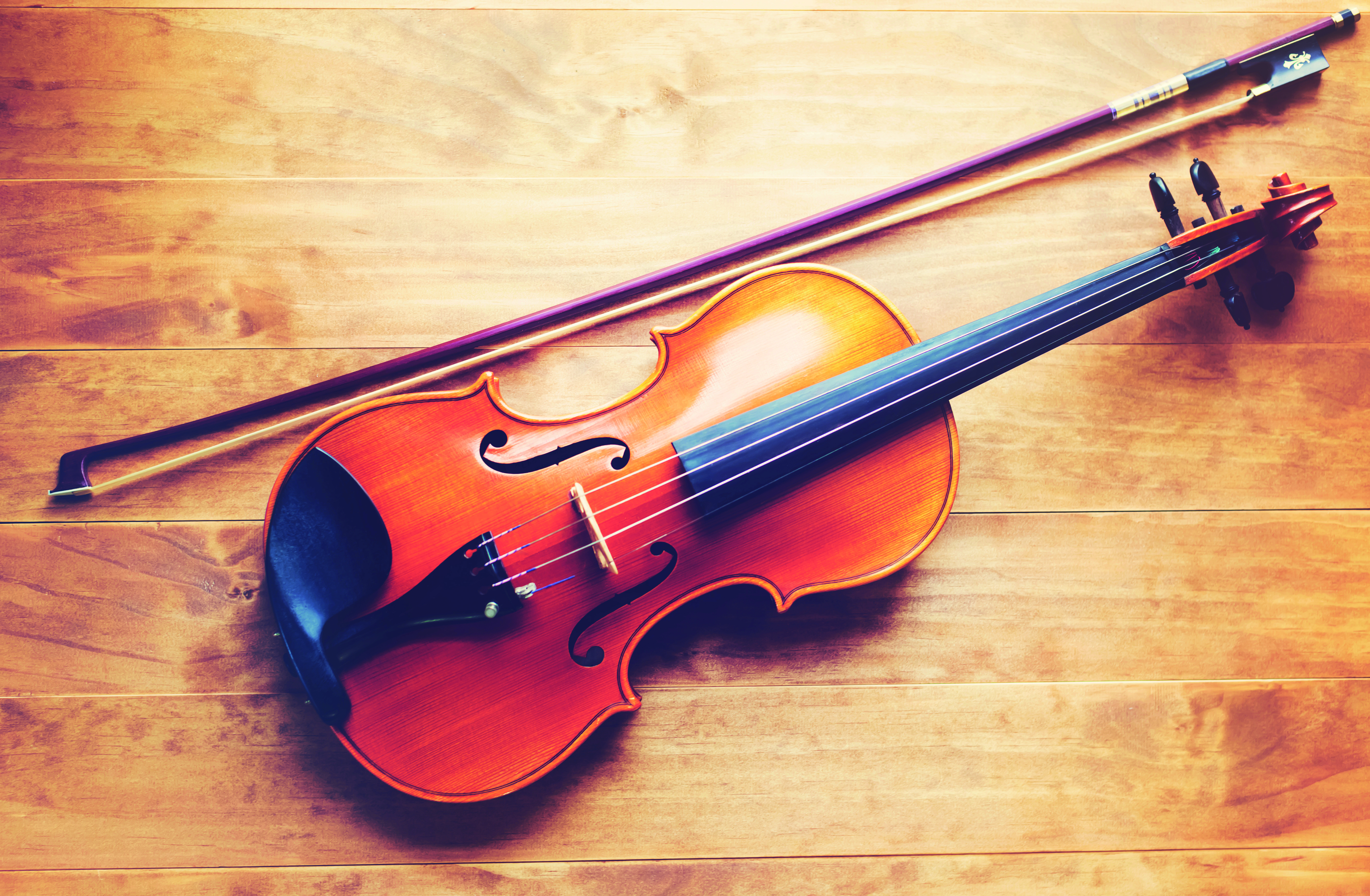 Violin and bow lying on a wooden textured table